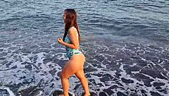 Horny teen shows off her big ass on the public beach, getting her pussy exposed outdoors