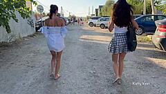 Two girls tease in public, flashing pussies without panties, small tits bouncing outdoors.