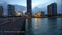 brunette flashes tits and ass while giving double handjob to big black monster cocks on public beach