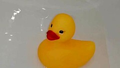 Mature blonde plays in the bathroom with a rubber duck. She enjoys the pool-like setting for relaxation.