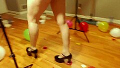 Fifi Foxx playfully pops colorful balloons while strutting in shiny high heels for fun.