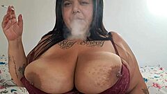 bbw woman relaxes in bedroom smoking while flashing her massive natural tits casually