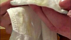 Brunette woman undresses slowly, revealing soiled underwear with visible discharge in close-up view